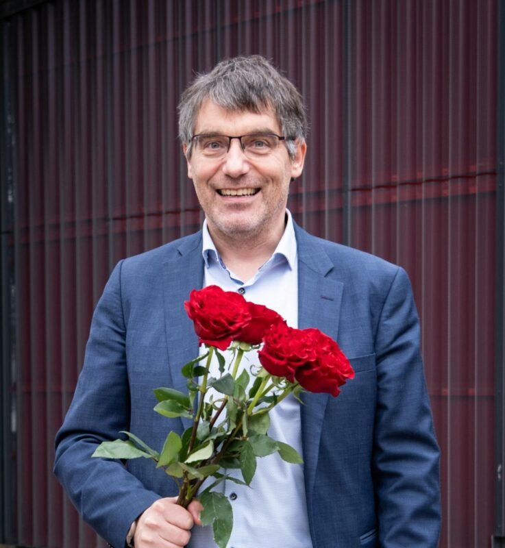 Photo portrait de Roger Nordmann, un bouquet de roses rouges à la main.